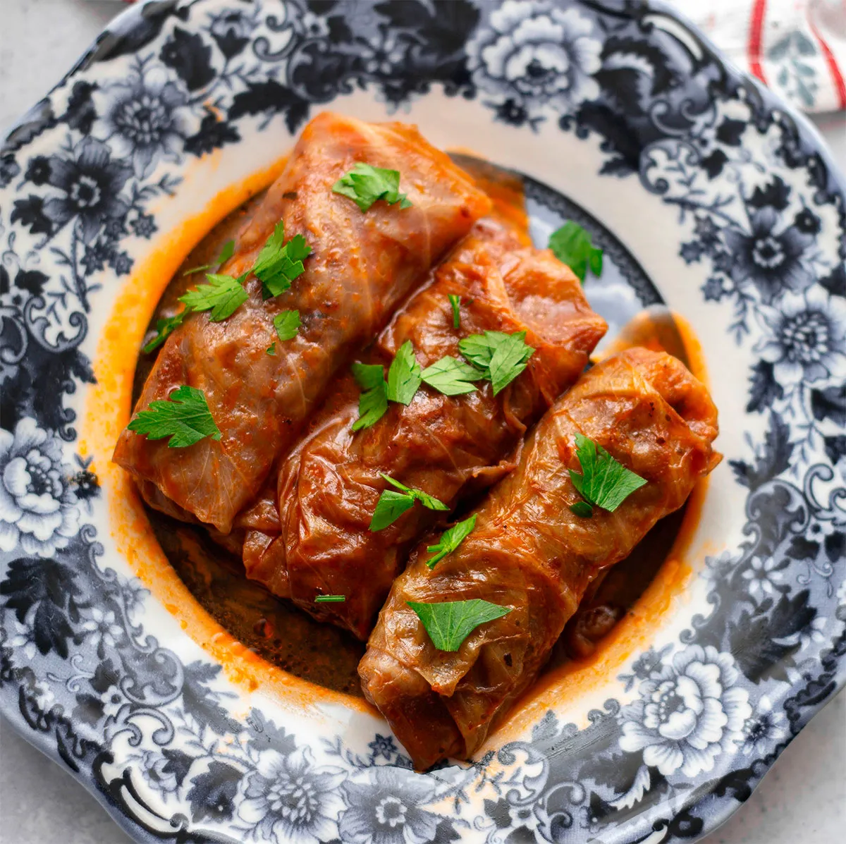 Вид сверху на вкусные фаршированные голубцы, украшенные зеленью, на декоративной цветочной тарелке. Автор: Zehra Yılmaz (Pixels)